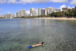A snorkeler explores the reefs off Oahu's Waikiki Beach, a great place for snorkeling in Hawaii.